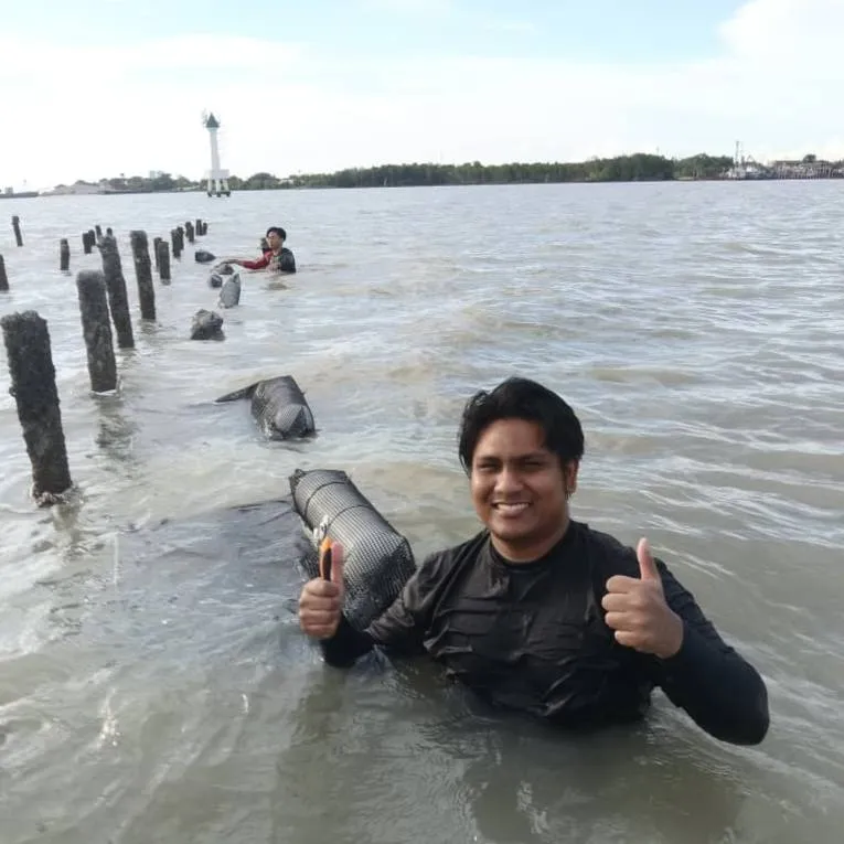 An Ocean Tide Ventures farmer standing chest-deep in the water beside an oyster line
