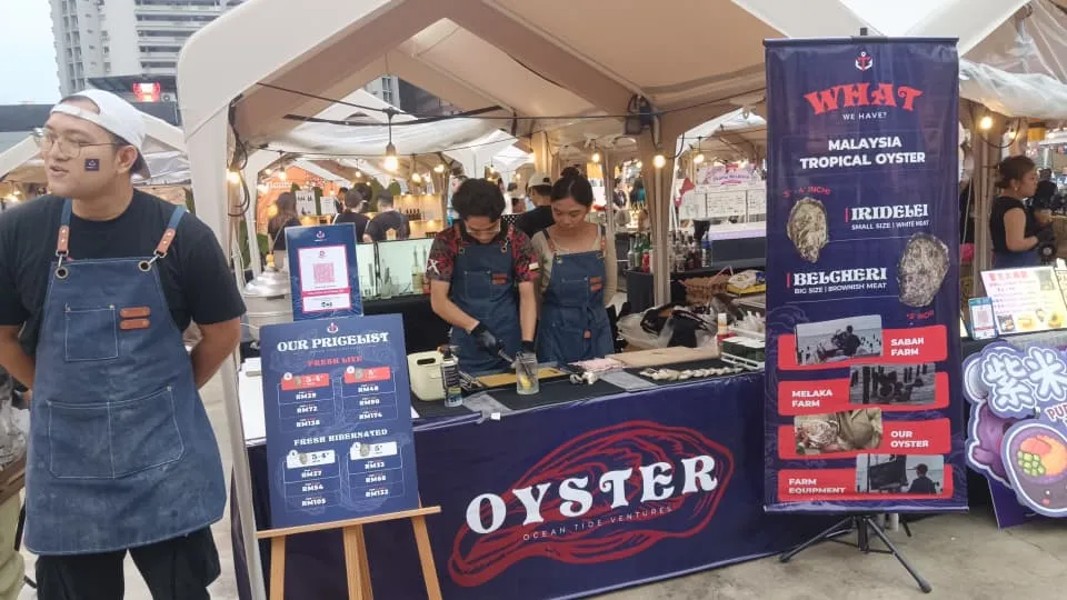 The Ocean Tide Ventures stall at Huhaland, the branded pricelist board and species banner up, crew shucking to order behind the counter