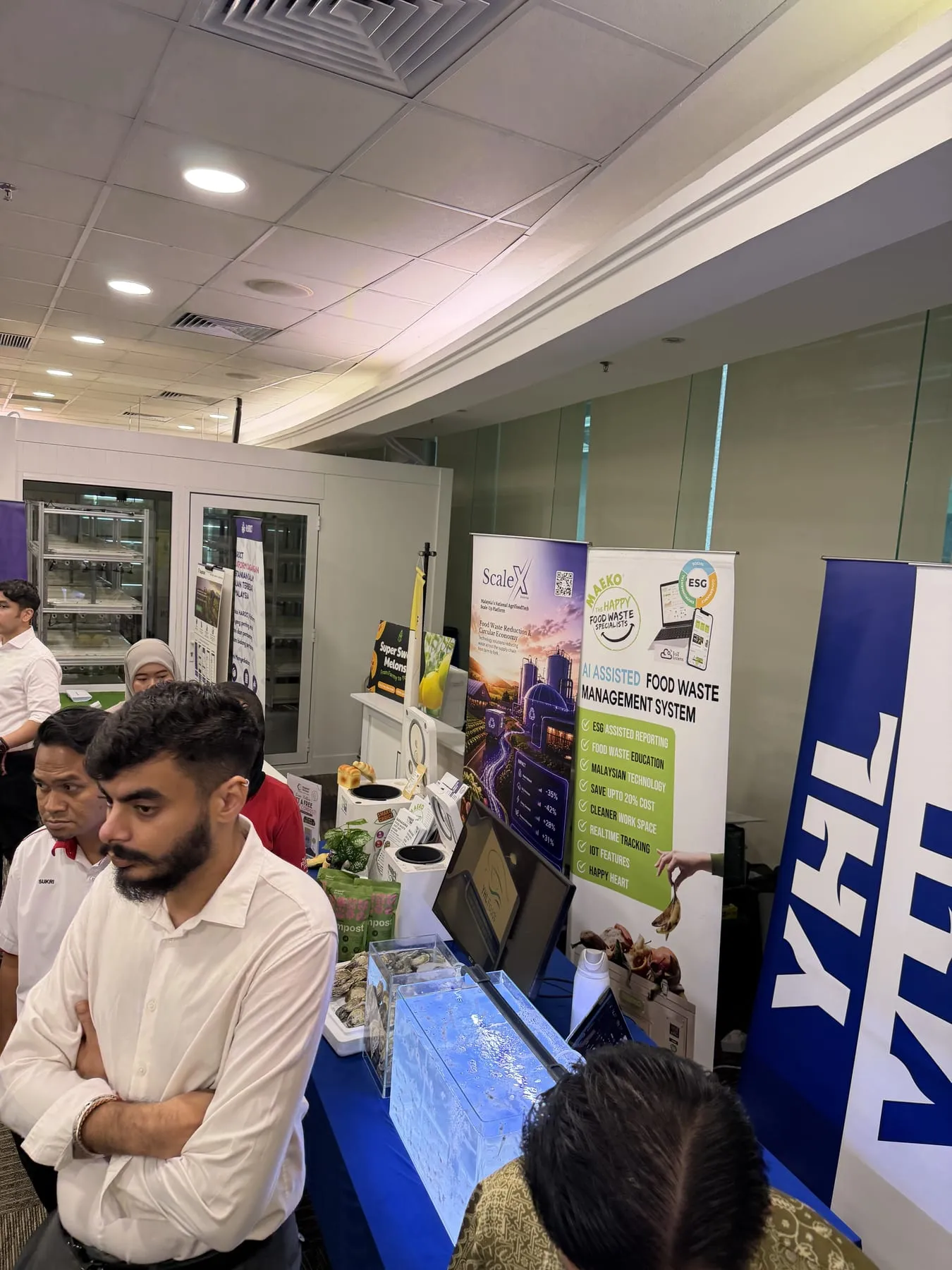A lit tank of oysters on an exhibition stand at the ScaleUp event, visitors at the counter and other exhibitors banners behind